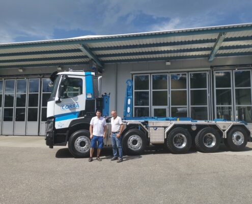 Nicola Corrà und Albert Corrà stehen vor ihrem Lastwagen mit dem neuen UT-Aufbau: Haken-Abrollkipper SAURIER 32TR80 VARITEC.